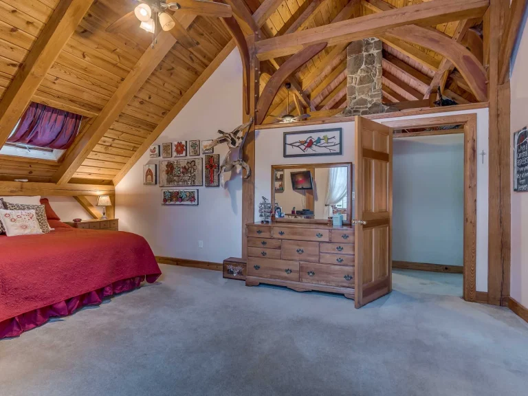 Timber frame bedroom with curved braces, pine ceiling and stone chimney