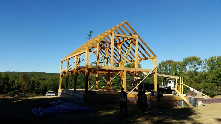 Timber frame house raising with the crew standing beside the frame