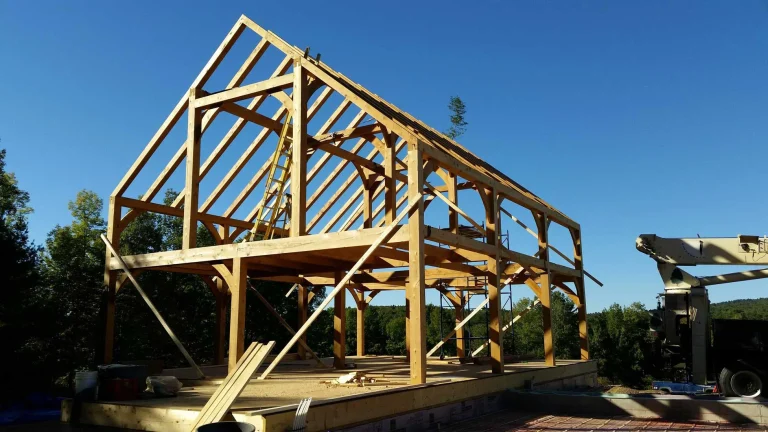 Two-story timber frame home structure raised against a blue sky