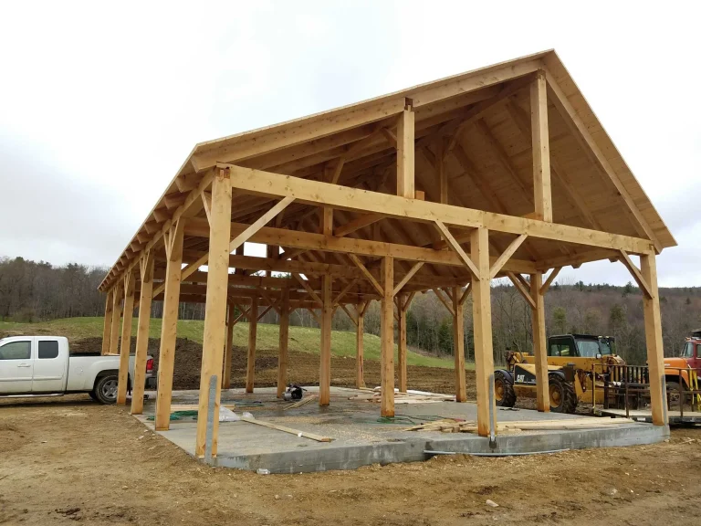 Open timber frame pole barn with braced posts on a concrete slab