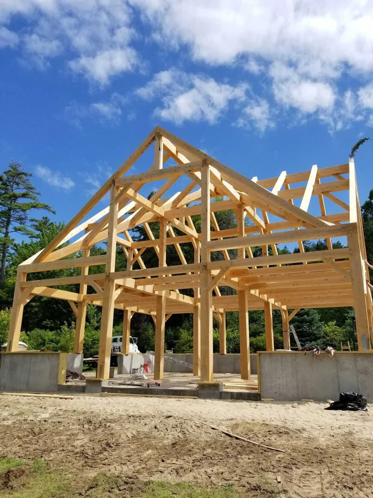 Timber frame bents and rafters raised on a poured foundation