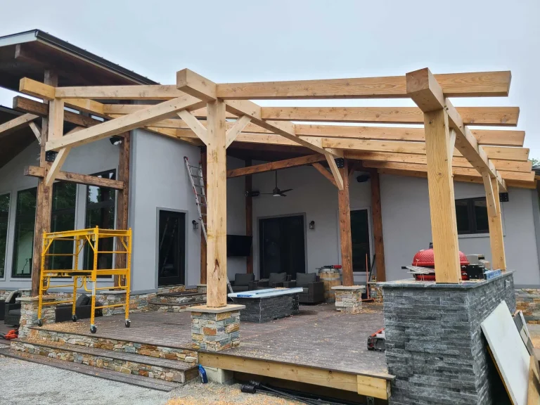 Timber frame pergola over a stone patio with an outdoor kitchen