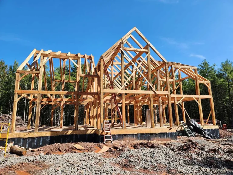 Two-story timber frame home with steep gables during construction