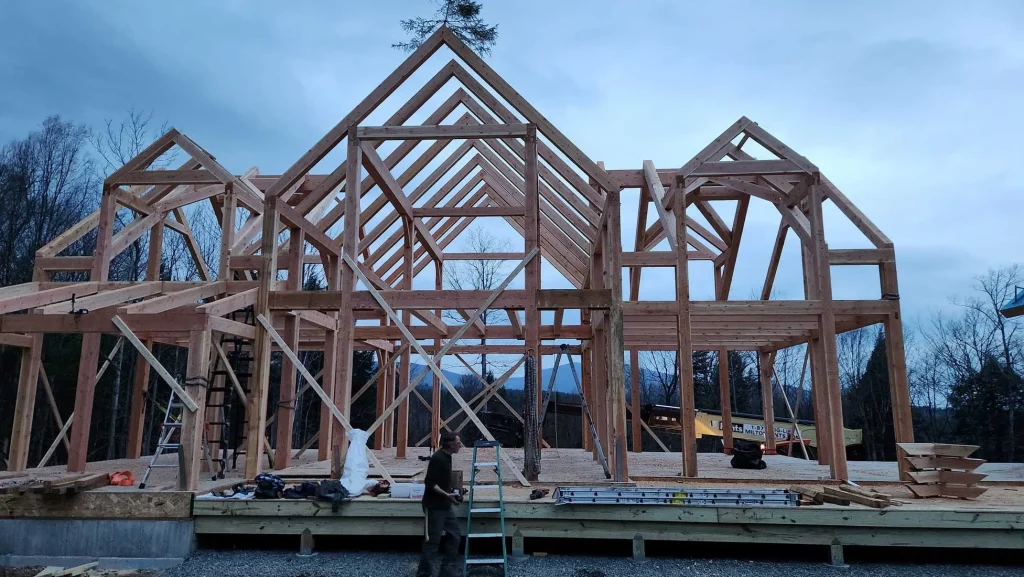Large timber frame home with three gables raised at dusk