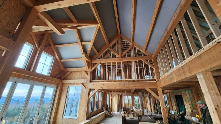 Timber frame great room under construction with tall gable windows