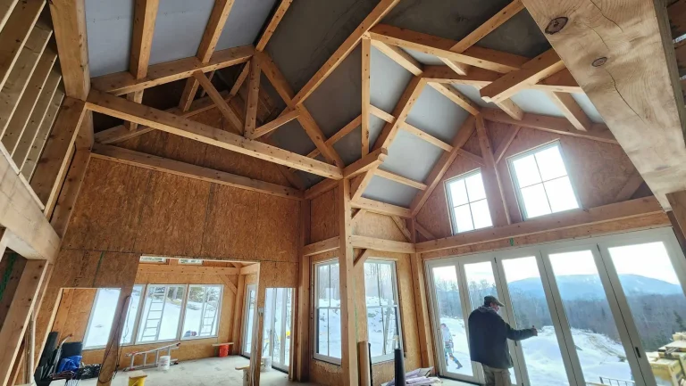 Timber frame great room under construction with trusses and tall windows