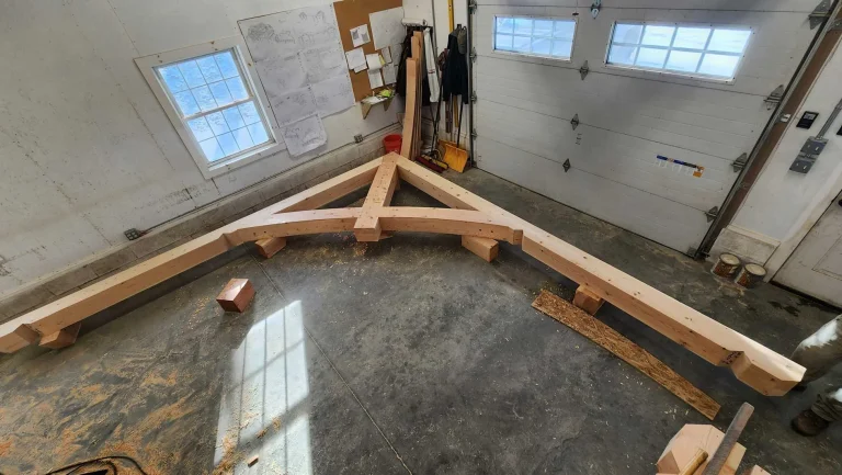 Hand-cut timber frame truss laid out on the shop floor before raising