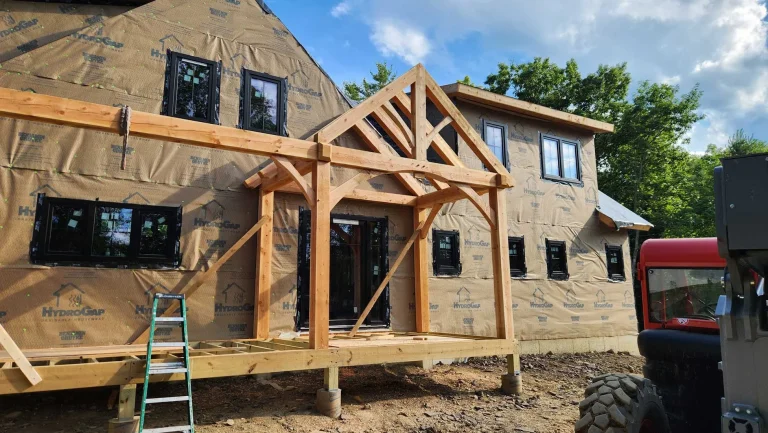 Timber frame entry porch with gable truss on a wrapped new home