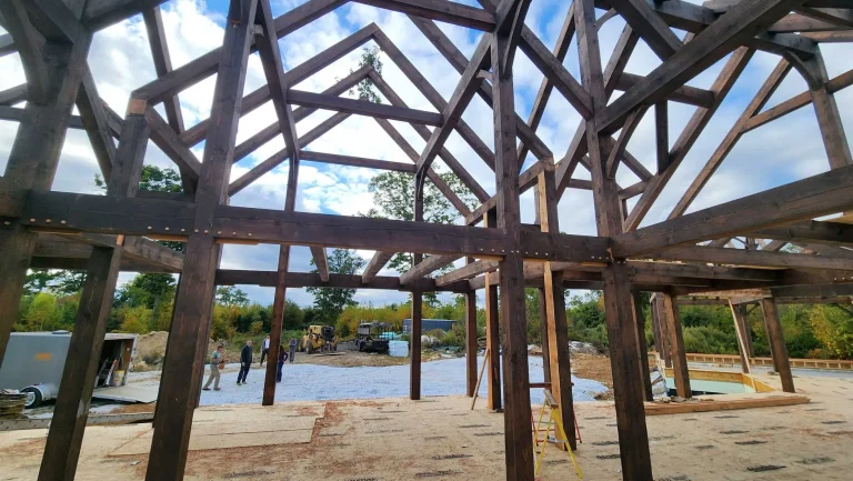 Dark-stained timber frame trusses and posts seen from inside the frame