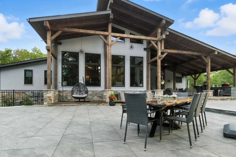 Timber frame covered patio pavilion with outdoor dining on a stone terrace