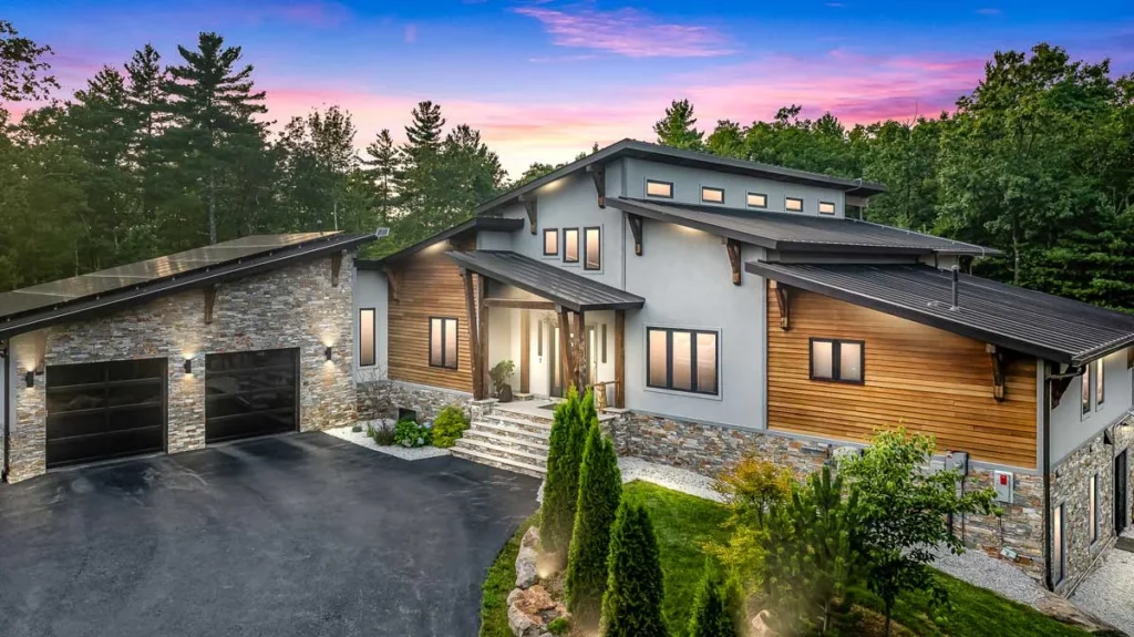 Modern timber accented home with stone and wood siding at dusk