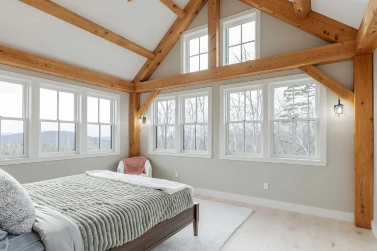 Timber frame bedroom with vaulted ceiling, exposed posts and walls of windows