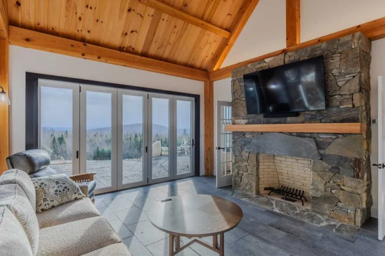 Timber frame sunroom with stone fireplace, pine ceiling and folding glass doors