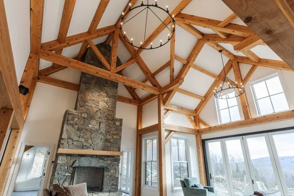 Vaulted timber frame great room with trusses, stone chimney and iron chandeliers