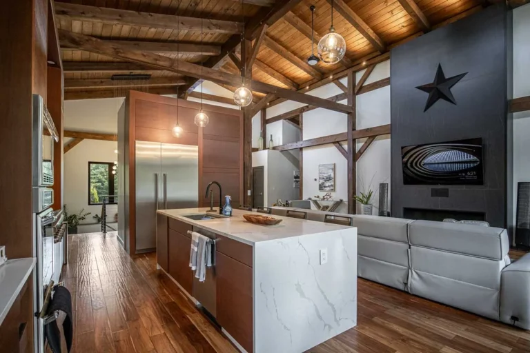 Timber frame kitchen with marble waterfall island, wood cabinets and exposed beams
